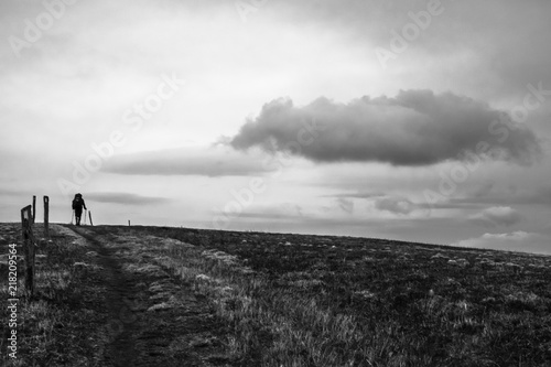 man on top of mountain hiking in ominous weather moody black and white photo