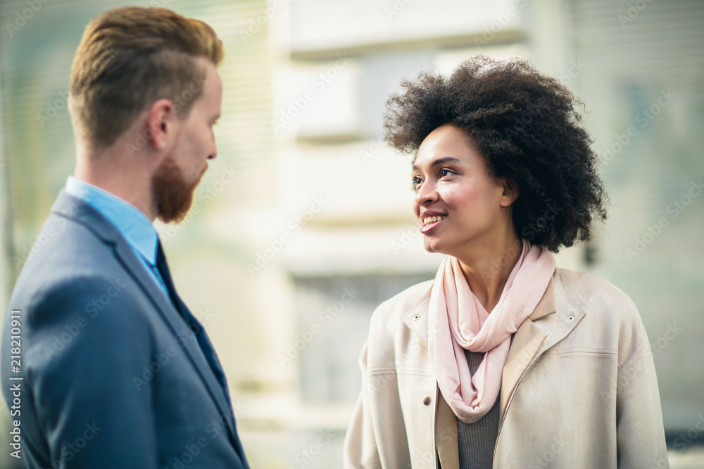 Two business people in an informal conversation in front of a business building Two business people in an informal conversation in front of a business building
