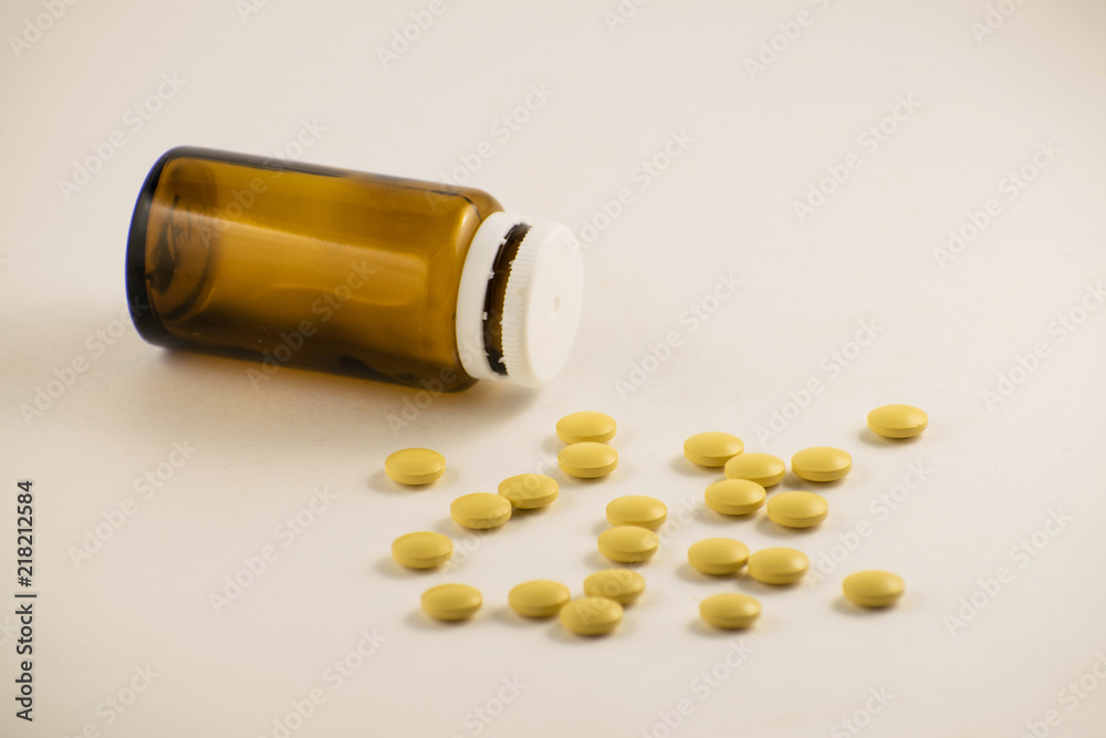Medicine bottle of brown glass with pills and tablets. Pills from bottle on the white background. Yellow pills in a bottle. Medicine bottle of brown glass with pills and tablets. Pills from bottle on the white background. Yellow pills in a bottle.
