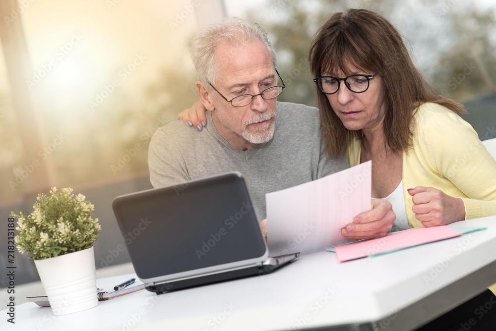 Senior couple checking financial document, light effect