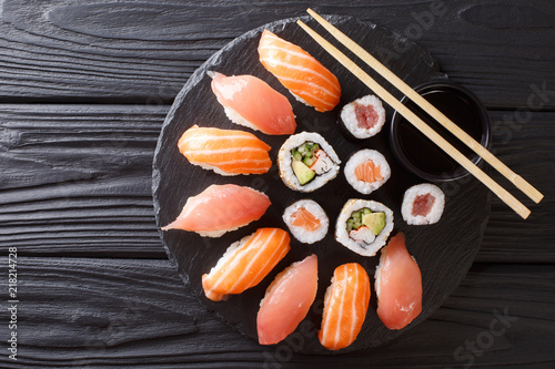 Sushi rolls set served on black stone slate on dark background. horizontal top view