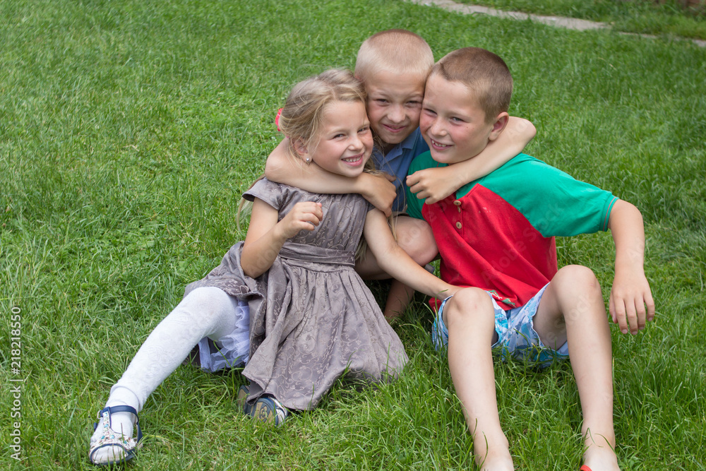 Obraz premium happy kids on the grass,children hugging themselves laughing while sitting on the grass