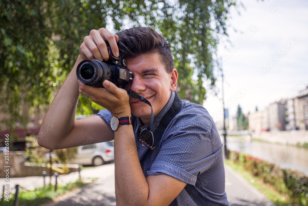 Close up view of young man with digital camera outdoors.Photographer photographing outdoor