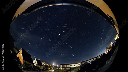 Perseids Meteorshower Shooting Stars Over A City At Night, a stack of some shooting stars from the perseids meteor shower of 2018 above grossenhain in saxony germany. photo