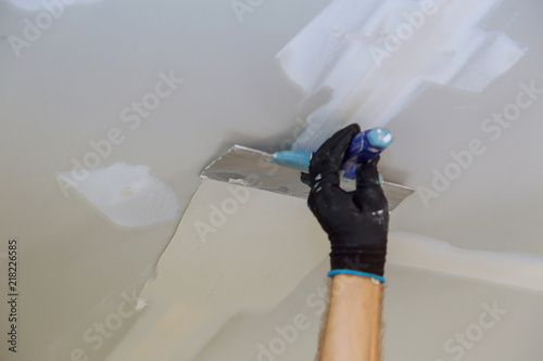 Man aligning a wall with spatula working with putty and spatula wall