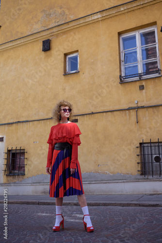 Young woman with curly hair in red retro dress. Walk around the city