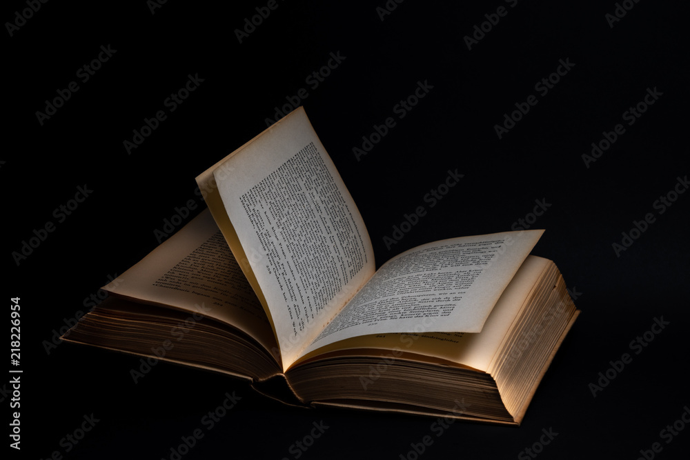Geöffnetes Buch auf schwarzem Hintergrund Geöffnetes Buch auf schwarzem Hintergrund