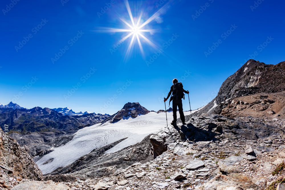 Hiker reaches a high mountain pass; he shows his joy at open arms. Val D'Aosta, Italy. 