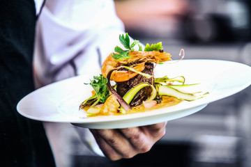 Modern food stylist decorating meal for presentation in restaurant. Closeup of food stylish. Restaurant serving. Close-up on the hand of a waiter carrying food