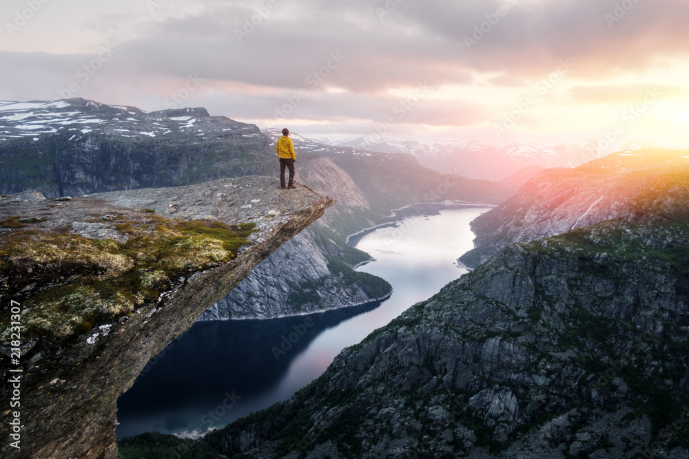 Fototapeta premium Sam turysta na skale Trolltunga - najbardziej spektakularny i słynny sceniczny klif w Norwegii