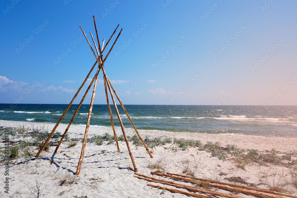 Foundation for Indian wigwam lodge or teepee made of pine wood at the seashore at summer. travel concept. copyspace