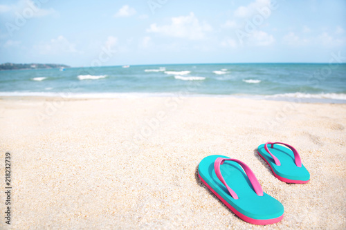 slipper of foot in sandals shoes and Blue ocean wave water distribution on sandy white beach, Sea background.The color of the water and beautifully bright. travel nature holiday summer concept.