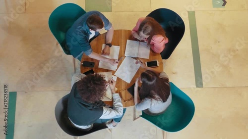 Multinational creative business team meeting and brainstorming at round table top view female team leader writes work plan on paper using pen diverse people group teamwork in modern start up office