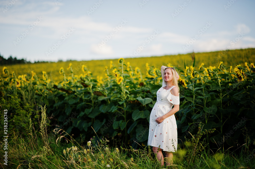 Blonde pregnant mother in sunflowers field. Happy moments of pregnancy. Blonde pregnant mother in sunflowers field. Happy moments of pregnancy.