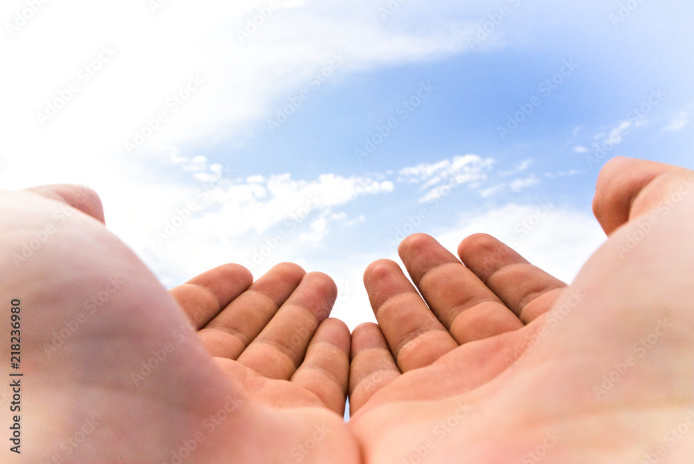 Hands cupped together on blue sky background Hands cupped together on blue sky background