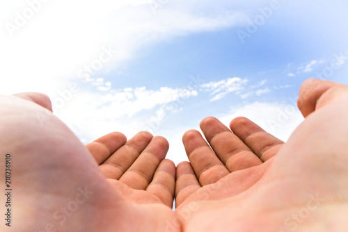 Hands cupped together on blue sky background