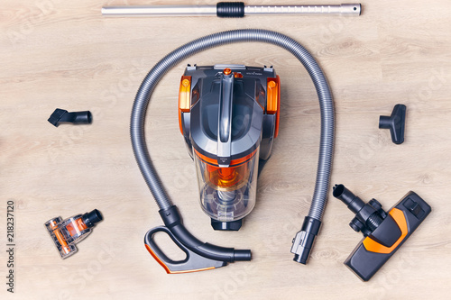 Top view of a modern vacuum cleaner with a container with nozzles and a hose spread out around it photo