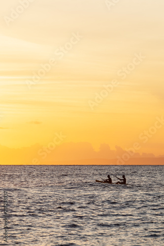 Silhouette of Two People Paddling in a Boat During Sunset. © carolinemaryan