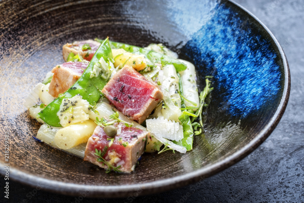 Modern fried tuna fish tataki filet salad with white asparagus sugar snaps and parmesan cheese as top view on a plate Modern fried tuna fish tataki filet salad with white asparagus sugar snaps and parmesan cheese as top view on a plate
