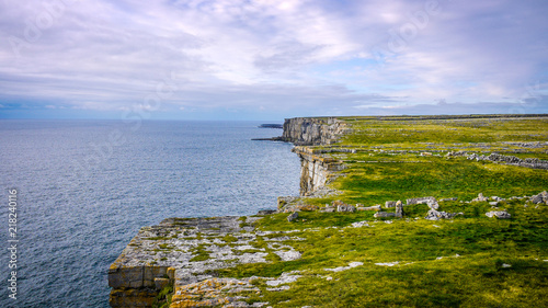 Beautiful view of the Inis Mór cliffs on a cloudy day. Taken from the top of the high cliff edge, showing the fields and ocean on a calm day.