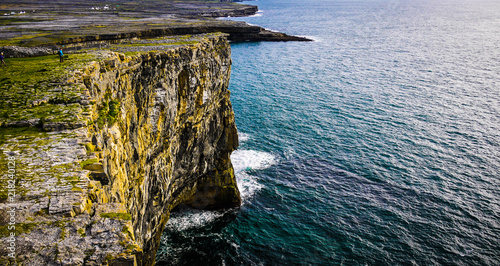Beautiful view of the Inis Mór cliffs on a cloudy day. Taken from the top of the high cliff edge, showing the fields and ocean on a calm day.