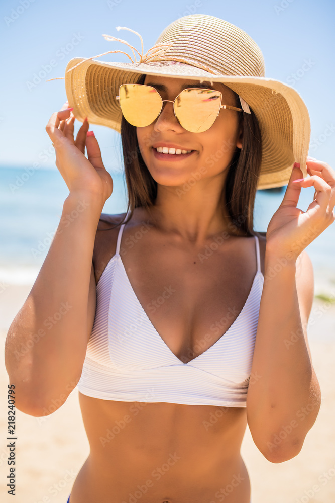 Stylish latin woman in straw hat and sunglasseson the beach on a sunny day
