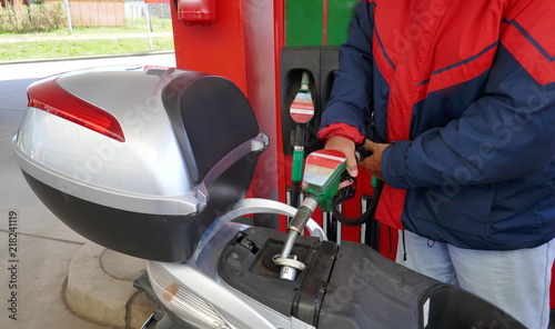 Ein Mann füllt den Tank seines Motorrollers mit Benzin an einer Tankstelle 