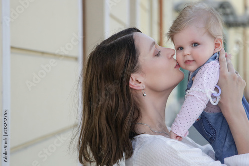 Young mother with her baby girl on the street, candid portrait image, natural lighting, family life concept   © triocean