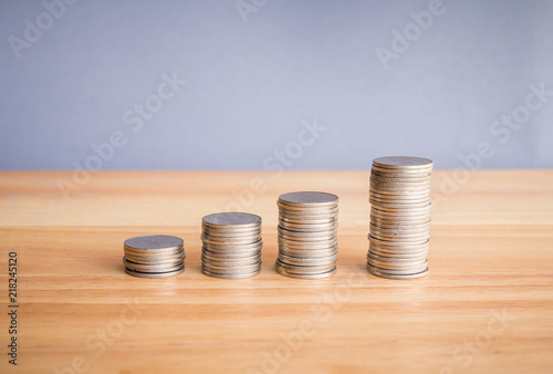 stacks of coin on wooden desk with grey background concept saving money. 