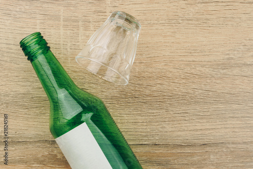 top view of soju bottle with glass on the wooden table. Soju is the colorless distilled beverage, the most popular liquor in Korea