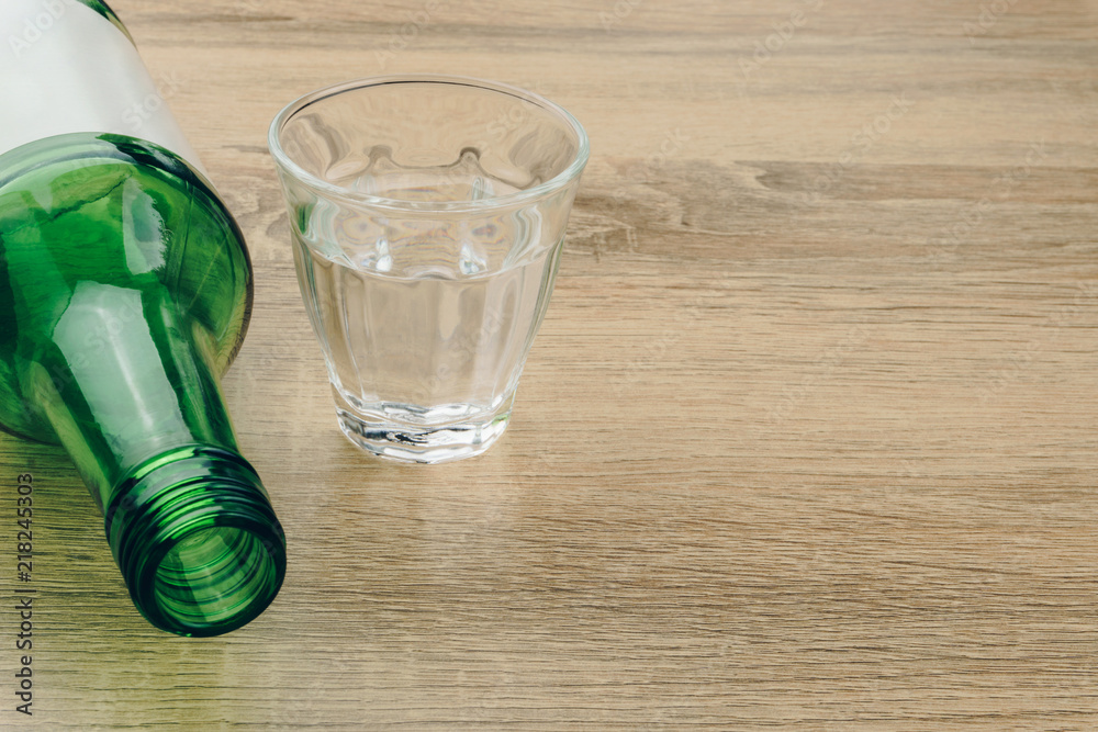 close up of soju bottle with glass on the wooden table. Soju is the