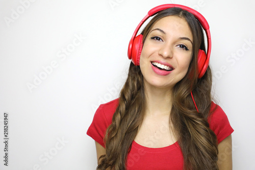 Cheerful young pretty girl smiling listening music in headphones over white background. Copy space.