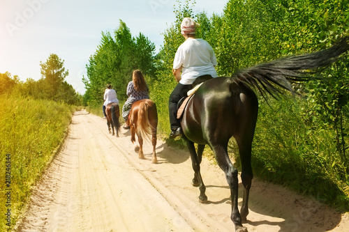Horse ride on a summer day. A group of tourists riding a horse with an instructor photo