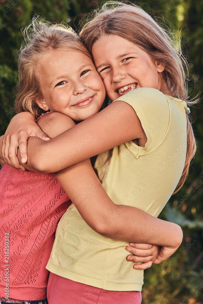 Close-up portrait of two happy girlfriends cuddling in the park. 