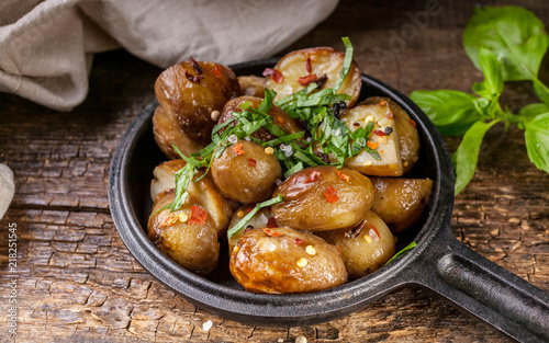 Baked potatoes in a frying pan with basil. Wooden background. Close-Up