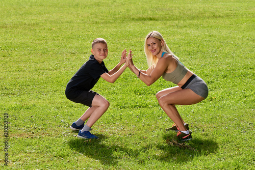 Sports family; mother and son doing sport exercises together outdoor