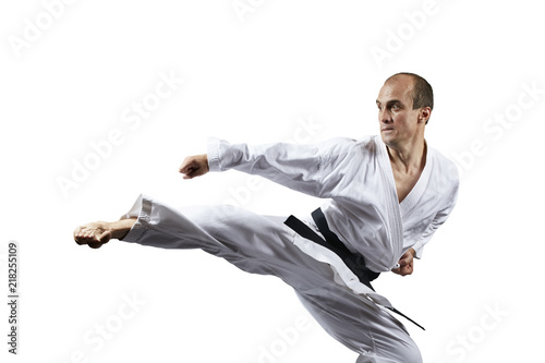 A kick struck by an athlete with a black belt on a white background isolated