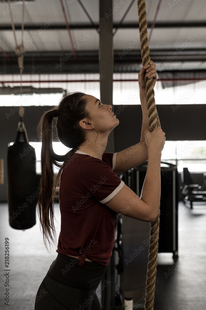 Woman doing rope climbing exercise in fitness gym Stock Photo