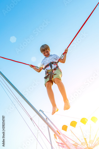 Smilling excited boy jumping on a trampoline with insurance.