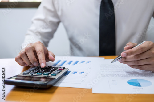 Male accountant calculations and analyzing financial graph data with calculator, Financing, Accounting, Doing finance, Economy, Savings Banking Concept