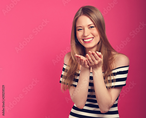 Beautiful sexy woman with enjoying eyes going to show the kissing sign the hands in fashion stripped dress on pink background. Toned closeup portrait photo