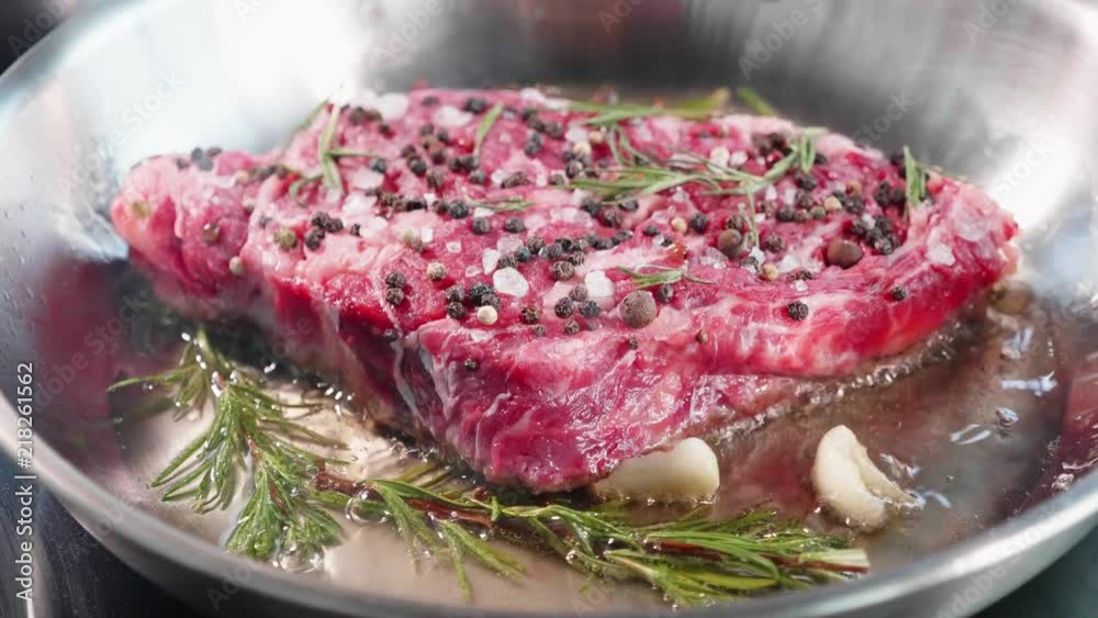 Meat steak with seasonings and herbs hissing on frying pan, close-up Meat steak with seasonings and herbs hissing on frying pan, close-up