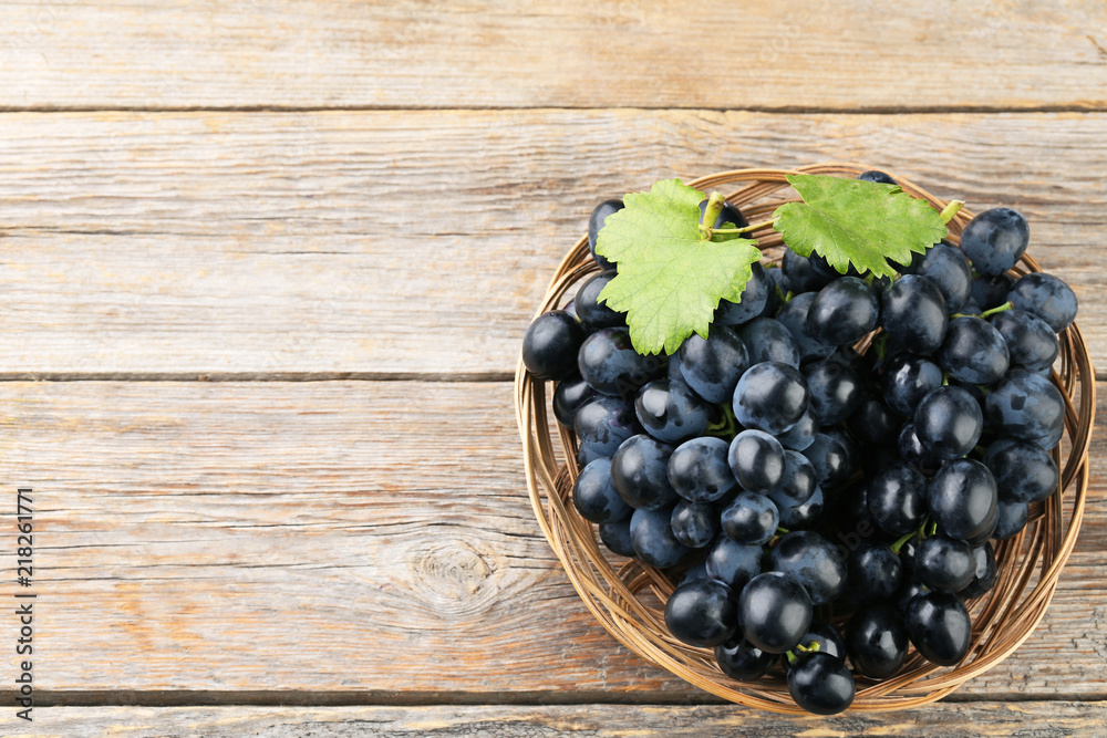 Blue grape in basket on grey wooden table Blue grape in basket on grey wooden table