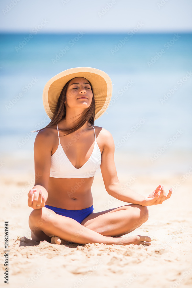Beautiful latin girl in yoga position on the beach during tropical vacation
