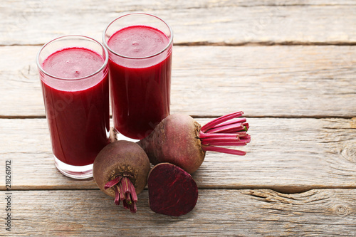 Fresh beets juice in glass on grey wooden table