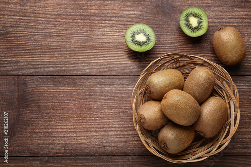 Fototapeta Naklejka Na Ścianę i Meble -  Kiwi fruits in basket on brown wooden table