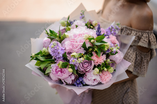 Fototapeta Naklejka Na Ścianę i Meble -  Young girl holding a bouquet of tender violet flowers