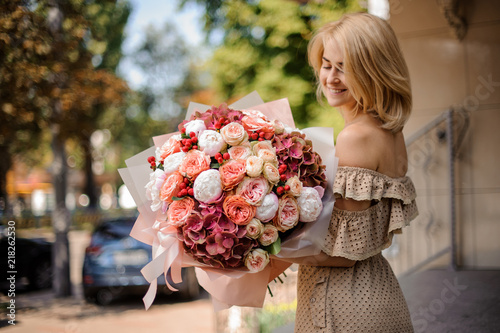 Smiling beautiful girl holding a bouquet of passionate flowers photo