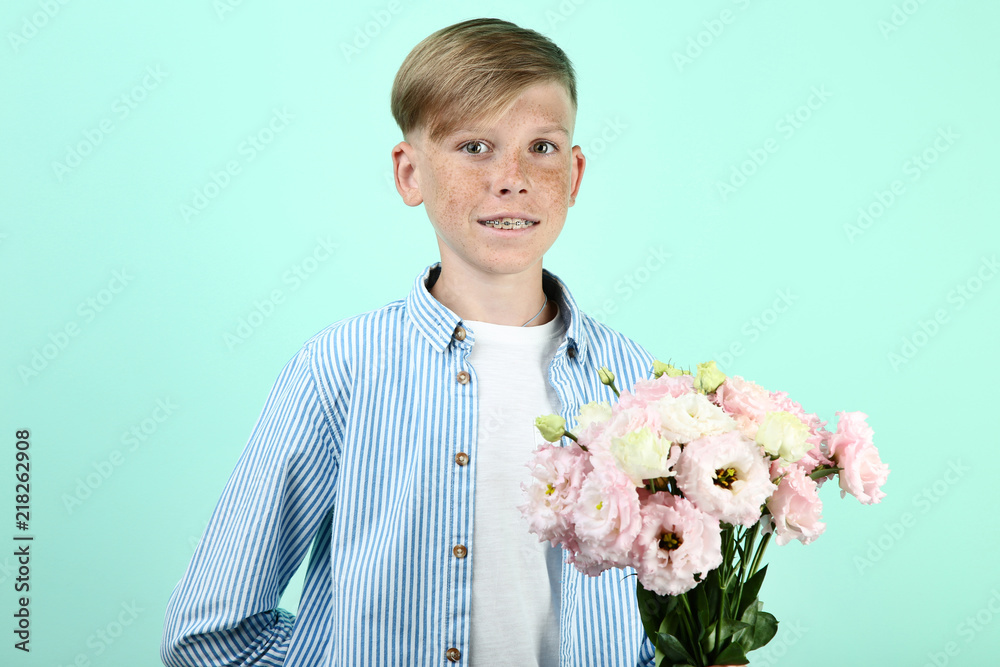 Beautiful young boy with eustoma flowers on mint background Beautiful young boy with eustoma flowers on mint background