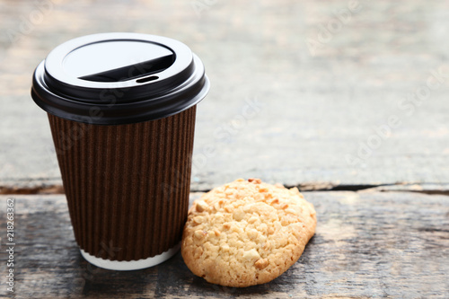 Paper cup of coffee with cookies on grey wooden table